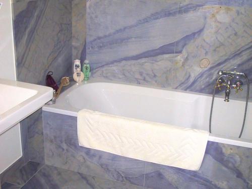 Modernes Badezimmer mit einer eingebauten Badewanne, umgeben von eleganten Azul-Bochira-Fliesen, die einzigartige blaue und graue Farbtöne aufweisen. Die Fliesen schaffen eine beruhigende und luxuriöse Atmosphäre, die zum Entspannen einlädt