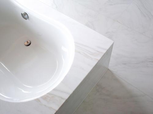 Eindrucksvolle Wand- und Bodenfliesen im Badezimmer aus Covelano Vena Oro Marmor, charakterisiert durch ihre leuchtend weiße Farbe mit markanten goldenen Venen, die eine luxuriöse und ansprechende Optik bieten. Die polierte Oberfläche dieser Fliesen reflektiert das Licht sanft und verstärkt das Gefühl von Weite und Eleganz im Raum